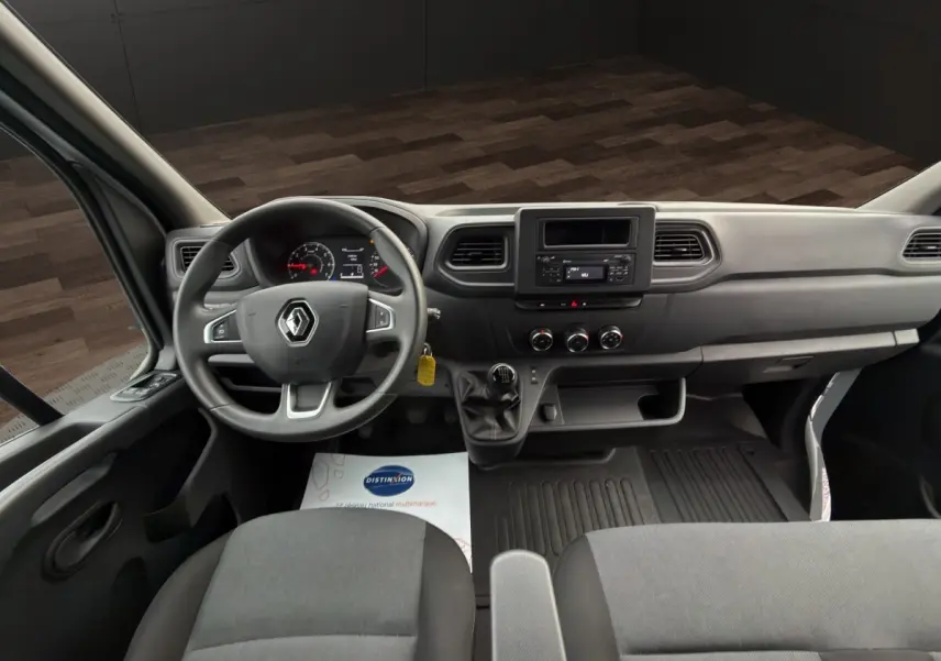 Vue intérieure avant du Renault Master 2024, tableau de bord gris avec volant multifonctions et boîte manuelle.