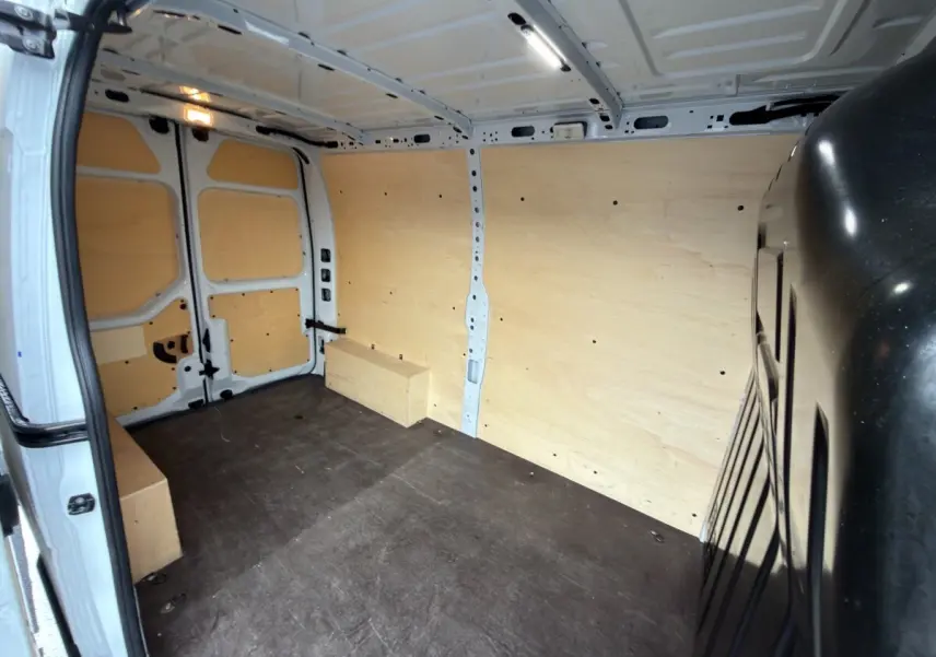 Vue intérieure arrière du Renault Master blanc 2024 avec aménagement complet en bois clair dans l’espace de chargement.
