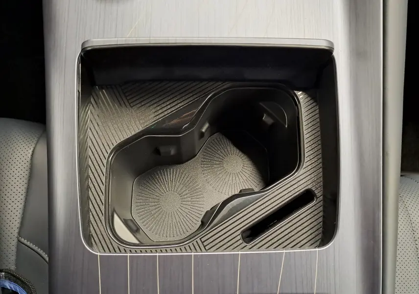 Gros plan sur le porte-gobelets noir intégré à la console centrale avec finition bois gris dans une Geely E5 PRO 2026.