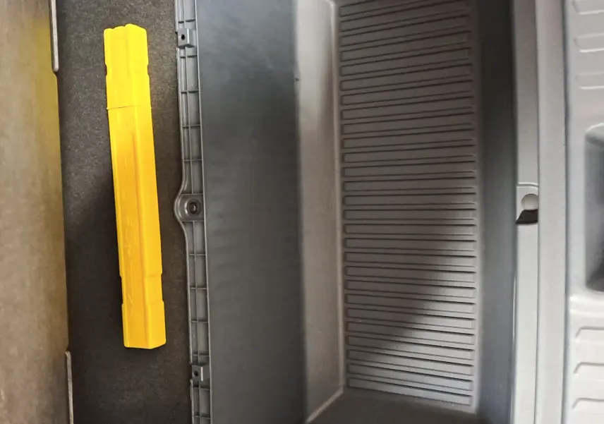 Coffre de rangement intérieur gris avec un triangle de sécurité jaune visible dans un GEELY E5 PRO 2026.