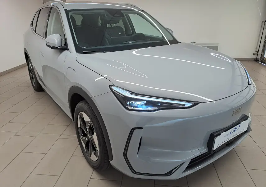 Vue 3/4 avant gauche du SUV électrique Geely E5 PRO 218ch gris Moonlight avec phares LED allumés en intérieur.