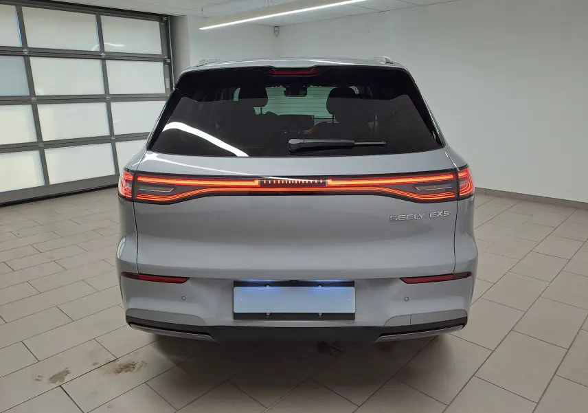 Vue arrière d'un SUV électrique Geely E5 PRO gris Moonlight de 2026 avec feux arrière LED continus allumés en intérieur.
