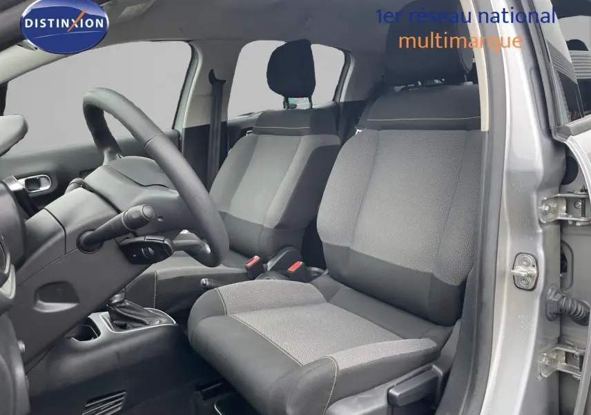 Vue intérieure côté conducteur de la Citroën C3 2023 gris acier, sièges tissu gris et noir avec coutures contrastées.