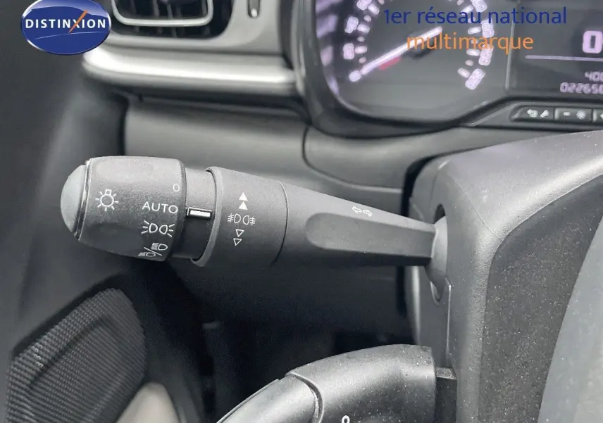 Gros plan sur la commande des phares à gauche du volant dans l'habitacle d'une Citroën C3 gris acier 2023.