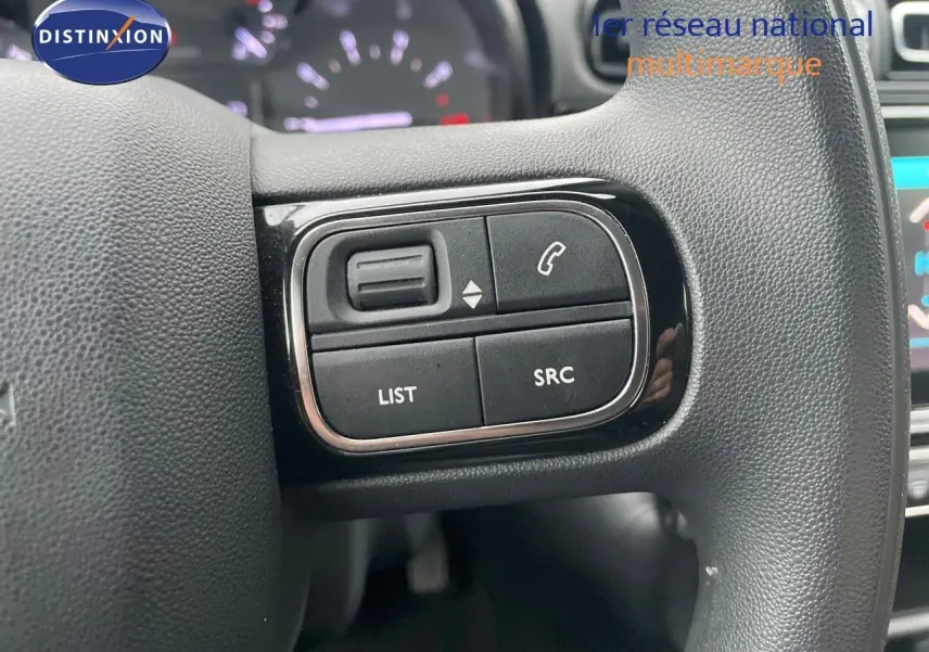Gros plan sur les commandes du volant d'une Citroën C3 gris acier 2023, avec boutons de gestion audio et appel.