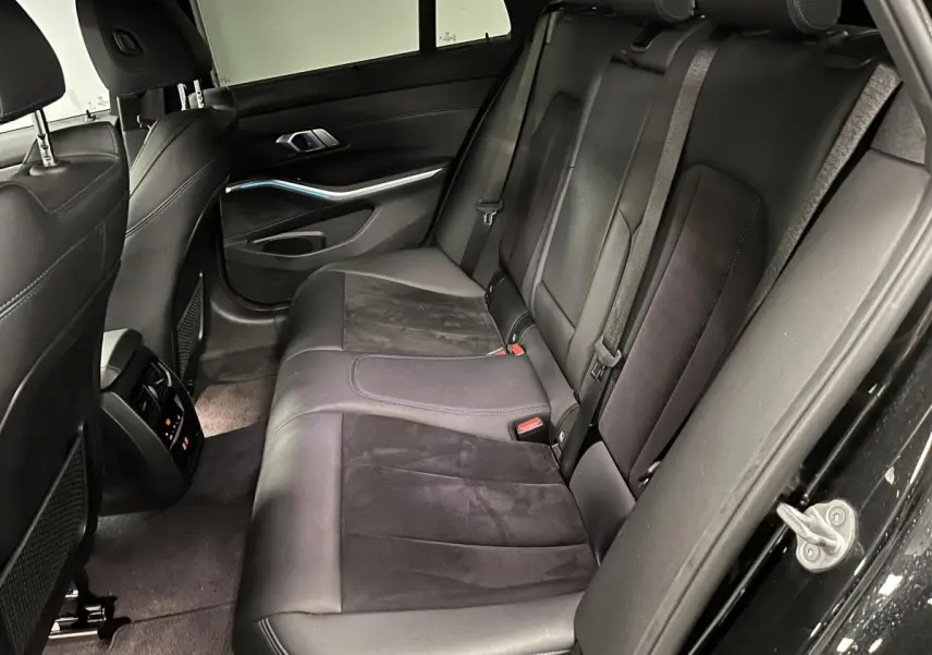 Vue côté droit de l'intérieur arrière noir de la BMW Série 3 320e Touring M Sport avec sellerie cuir et Alcantara.