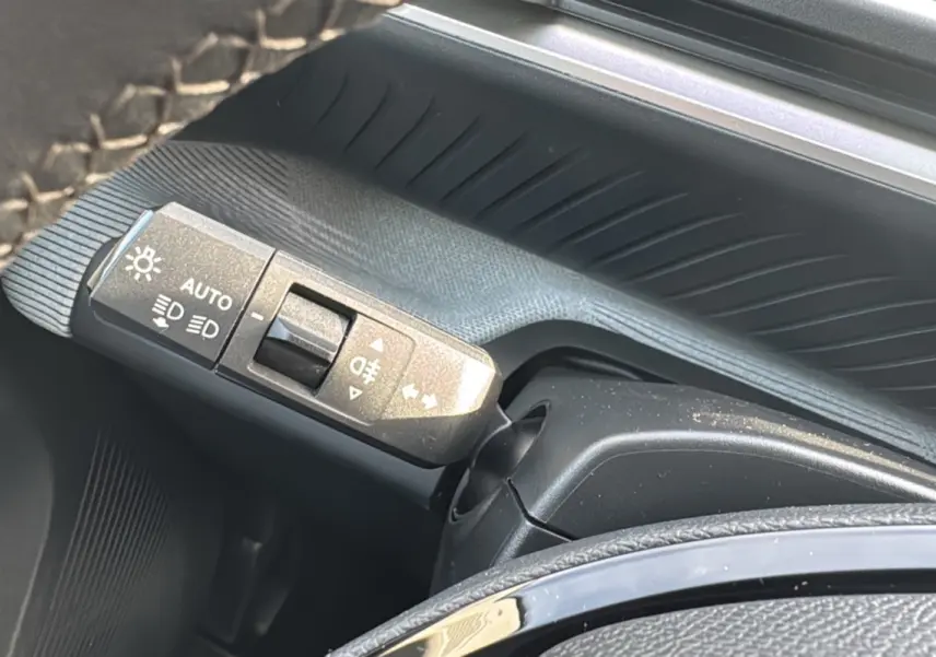 Gros plan sur la commande des feux au volant d'une Citroën C3 Aircross noir Perla Nera, finition 2025.