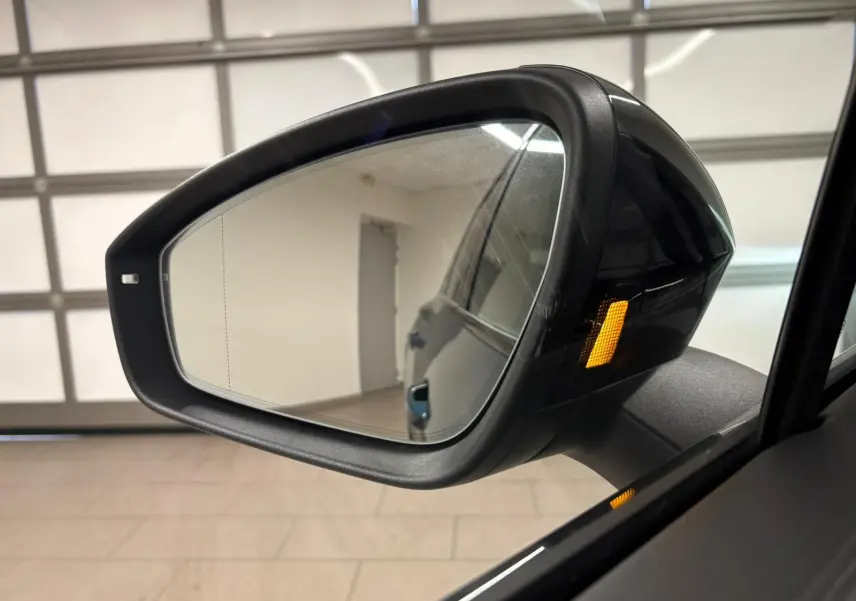 Rétroviseur côté droit du Volkswagen Tiguan Nightshade Blue 2024 avec clignotant latéral orange allumé.