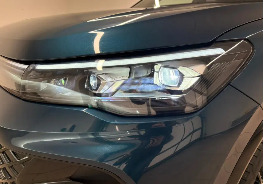 Gros plan sur le phare avant droit du Volkswagen Tiguan 2024 en Nightshade Blue avec éclairage LED IQ.Light.