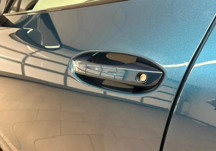 Poignée de porte côté gauche en gros plan sur Volkswagen Tiguan 2024 Nightshade Blue avec reflet intérieur.