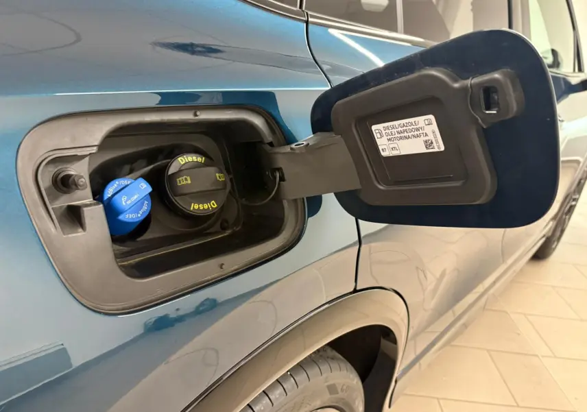 Gros plan sur la trappe à carburant ouverte côté gauche d’un Volkswagen Tiguan Nightshade Blue 2024 diesel.