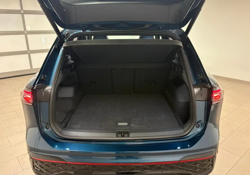 Vue arrière du Volkswagen Tiguan 2024 Nightshade Blue avec coffre ouvert et hayon électrique visible.