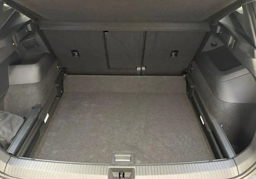 Coffre spacieux du Volkswagen Tiguan 2024 en Nightshade Blue, vue intérieure sans chargement, avec revêtement noir.