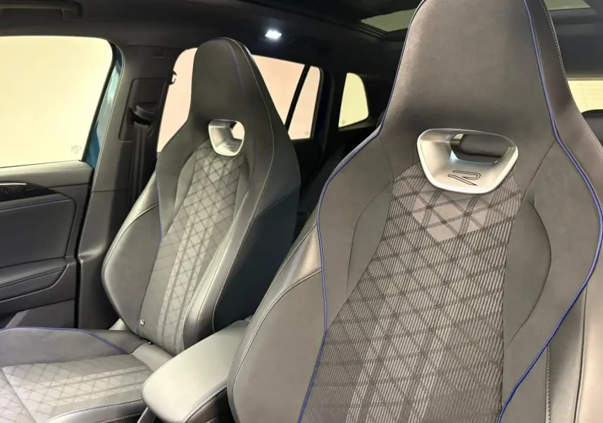 Vue intérieure rapprochée des sièges avant en cuir gris avec surpiqûres bleues du Volkswagen Tiguan 2024.