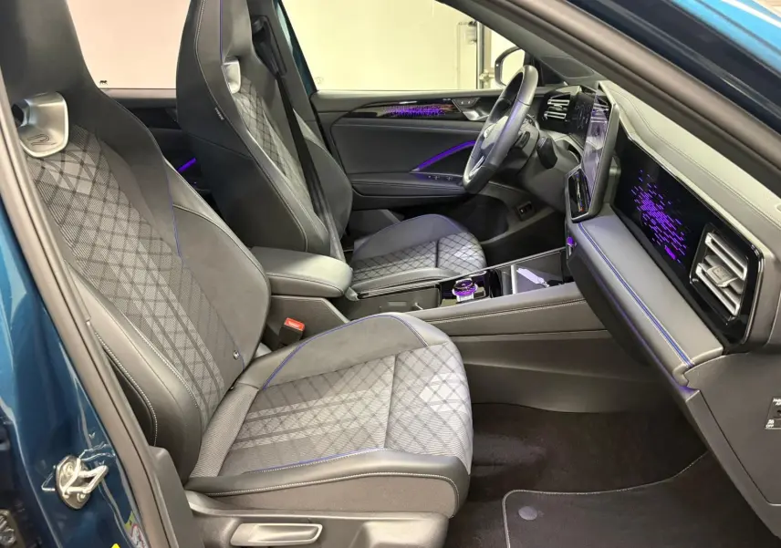 Vue intérieure côté conducteur du Volkswagen Tiguan 2024 Nightshade Blue, avec sièges en cuir et éclairage d'ambiance violet.