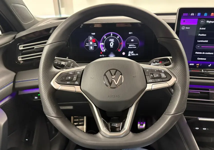 Vue rapprochée du volant en cuir perforé du Volkswagen Tiguan 2024 avec tableau de bord numérique et écran tactile.