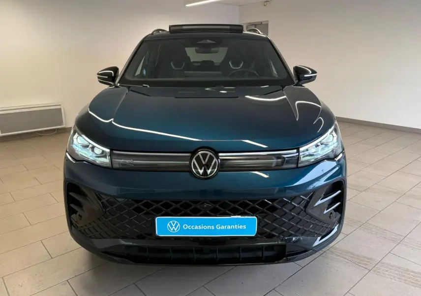 Vue avant d'un Volkswagen Tiguan 2024 Nightshade Blue avec calandre noire et phares LED matriciels allumés.