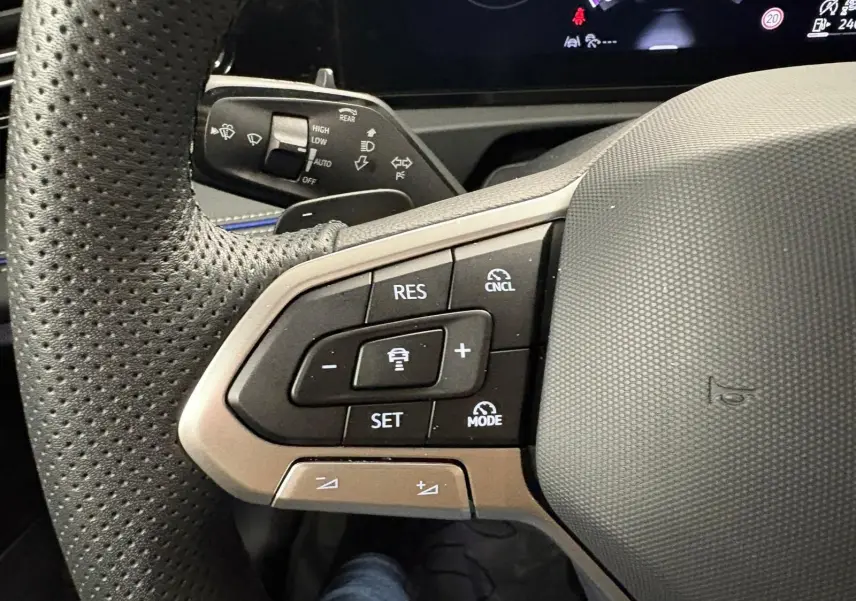 Gros plan sur les commandes au volant à gauche du Volkswagen Tiguan 2024, finition Black R-Line, volant en cuir perforé.