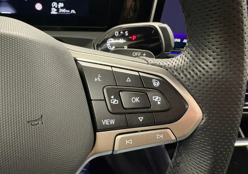 Gros plan sur les commandes multifonctions à droite du volant perforé du Volkswagen Tiguan 2024, intérieur noir.