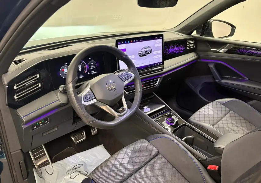 Vue intérieure côté conducteur du Volkswagen Tiguan 2024 avec tableau de bord numérique et éclairage d’ambiance violet.
