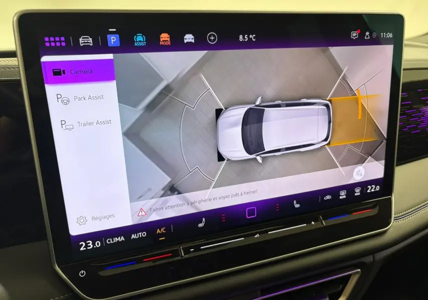Écran tactile intérieur montrant l'assistance au stationnement avec vue aérienne du Volkswagen Tiguan blanc.