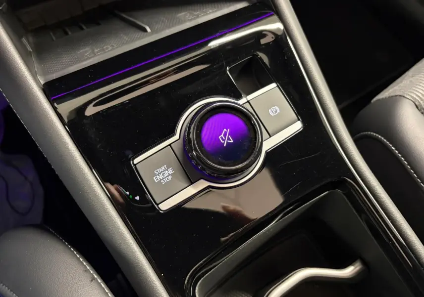 Gros plan sur la console centrale noire brillante du Volkswagen Tiguan 2024 avec bouton start/stop et molette tactile.