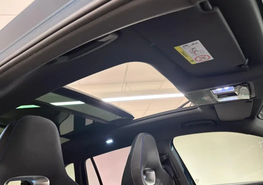 Vue intérieure du toit ouvrant panoramique ouvert du Volkswagen Tiguan Nightshade Blue 2024, avec sièges avant visibles.