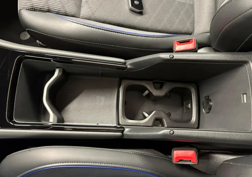 Vue plongeante sur la console centrale noire du Volkswagen Tiguan 2024 avec porte-gobelets et accoudoir entre sièges.