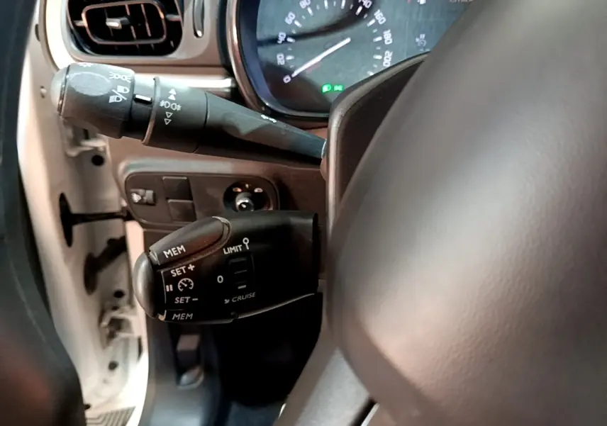 Vue rapprochée du commodo de régulateur de vitesse côté gauche du volant dans une Citroën C3 blanche de 2020.