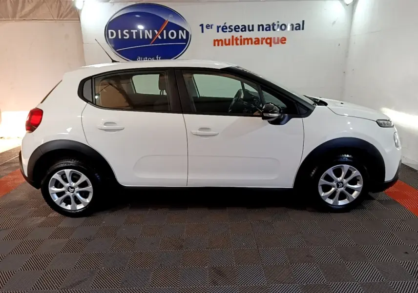 Profil côté gauche d'une Citroën C3 blanche 2020, avec protections noires sur les passages de roues et jantes argentées.