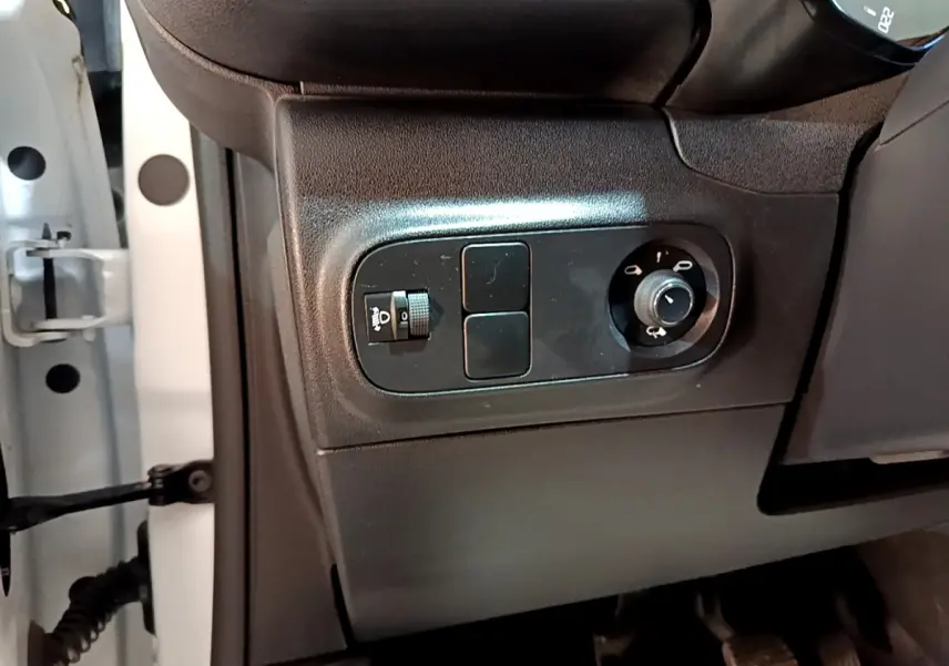 Vue rapprochée côté gauche du tableau de bord noir de la Citroën C3 blanche, avec commandes des phares et rétroviseurs.