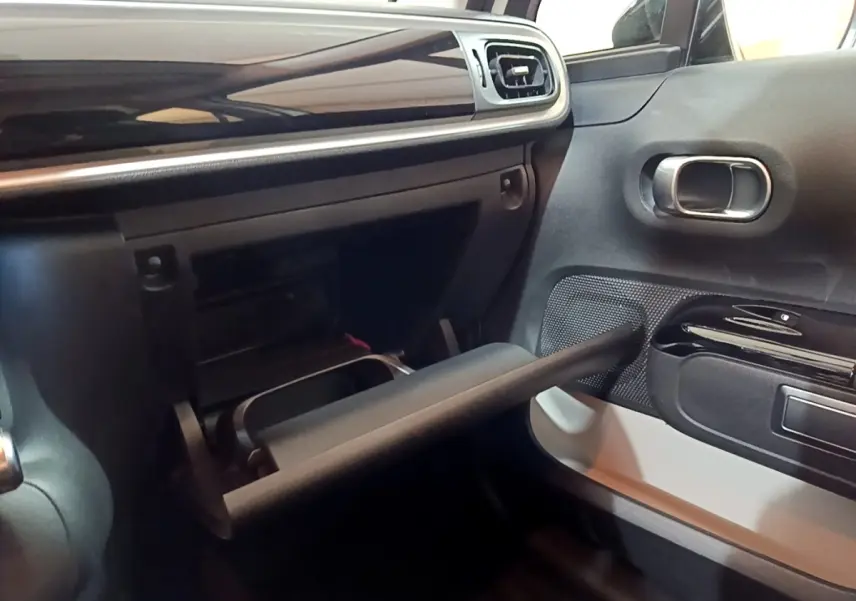 Vue intérieure côté passager du tableau de bord noir et gris avec boîte à gants ouverte d'une Citroën C3 blanche 2020.