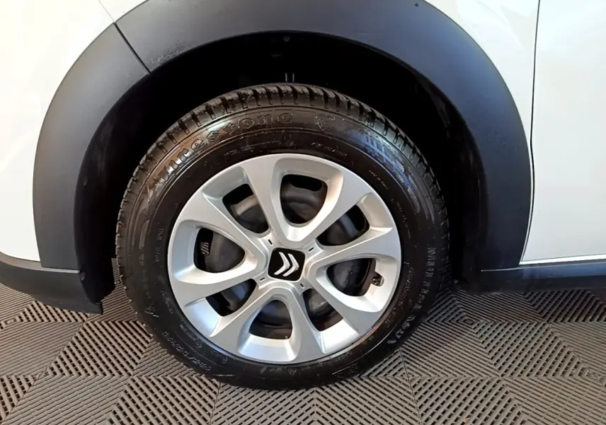 Gros plan sur la roue avant gauche d'une Citroën C3 blanche avec jante alliage et passage de roue noir mat.