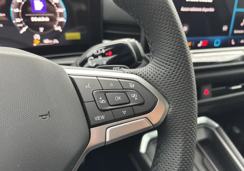 Gros plan sur les commandes multifonctions du volant cuir perforé du Volkswagen T-Roc 2026 version R-Line.