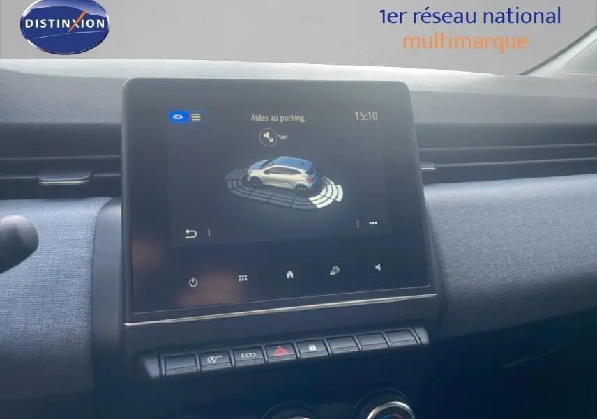 Vue rapprochée de l’écran tactile central affichant l’aide au parking dans l’habitacle d’une Renault Clio blanche.