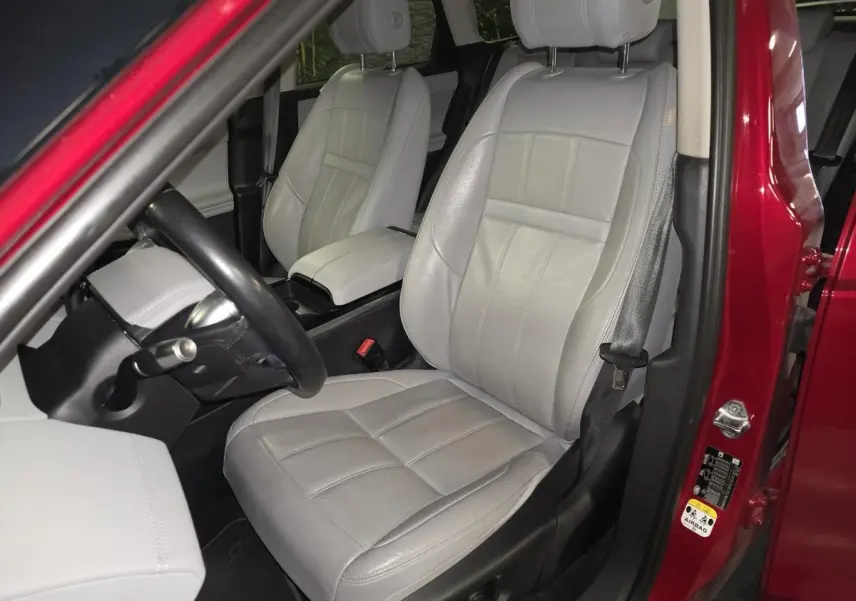 Vue intérieure côté conducteur du Range Rover Evoque rouge de 2019, avec sièges en cuir gris clair et volant noir.