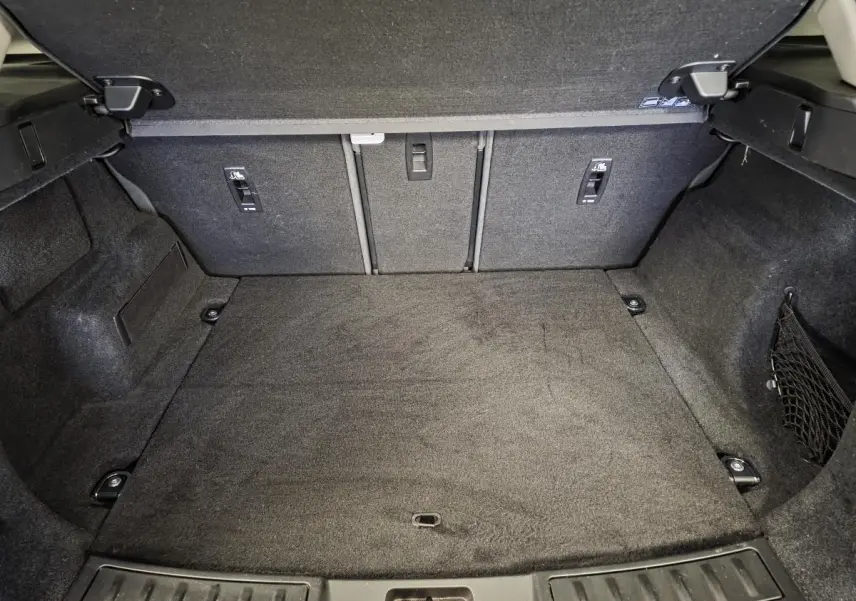Coffre ouvert vu de l'arrière du Range Rover Evoque rouge, espace de chargement vide et revêtement noir.