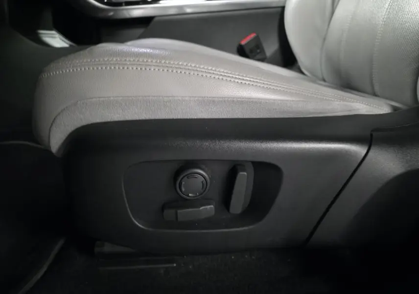 Détail du siège avant en cuir gris clair avec commandes électriques sur le côté droit du Range Rover Evoque rouge.