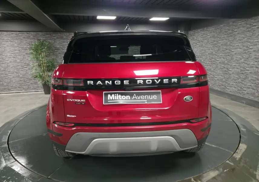 Vue arrière d'un Range Rover Evoque rouge avec toit noir et logo distinctif sur un plateau tournant intérieur.