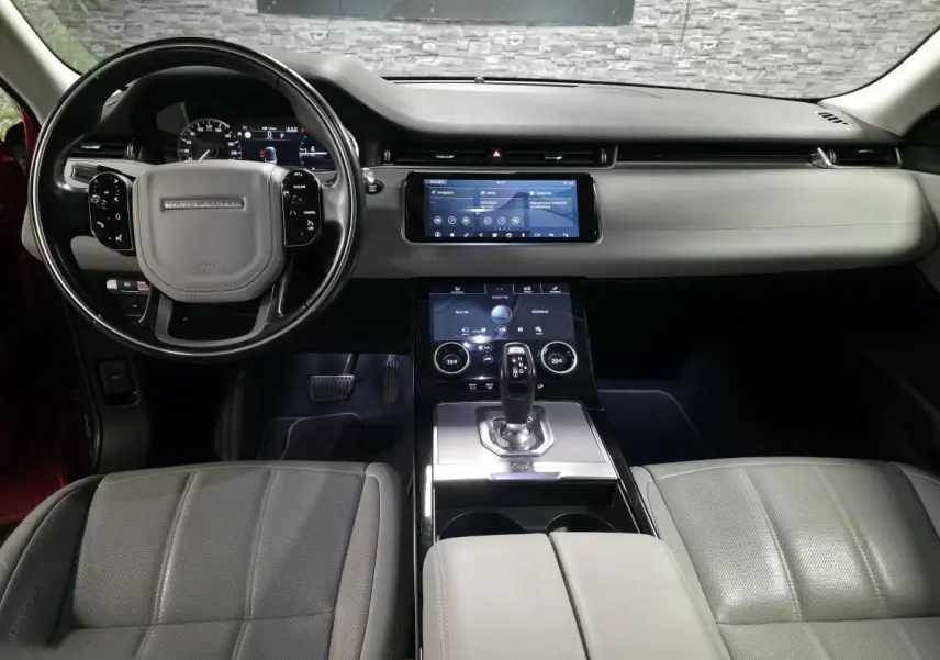 Vue intérieure avant du Range Rover Evoque 2019 avec tableau de bord noir et sièges cuir gris clair.