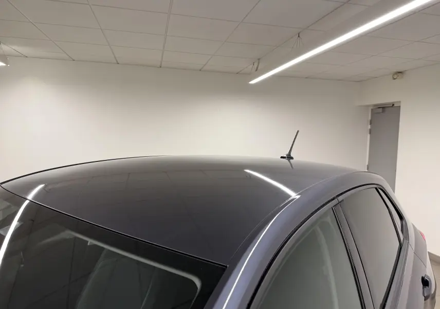 Vue rapprochée du toit gris cendre de la Volkswagen Polo 2025 avec antenne et vitres teintées dans un intérieur blanc.