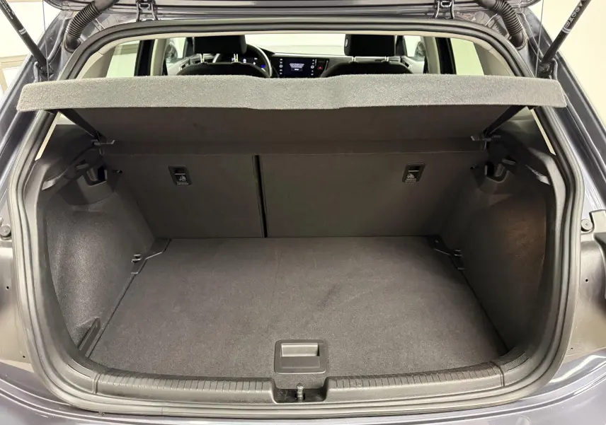 Vue arrière du coffre ouvert d'une Volkswagen Polo gris cendre, montrant l'espace de chargement et la tablette cache-bagages.