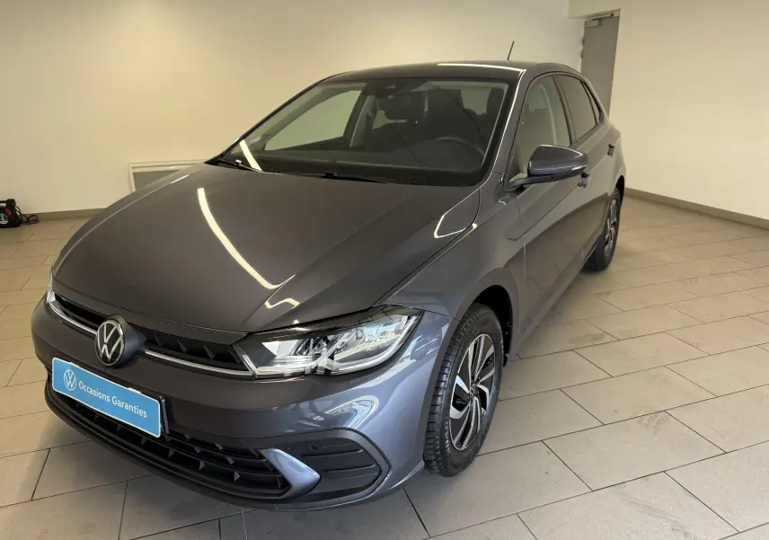 Volkswagen Polo gris cendre vue 3/4 avant droit, avec jantes alliage et calandre noire brillante.