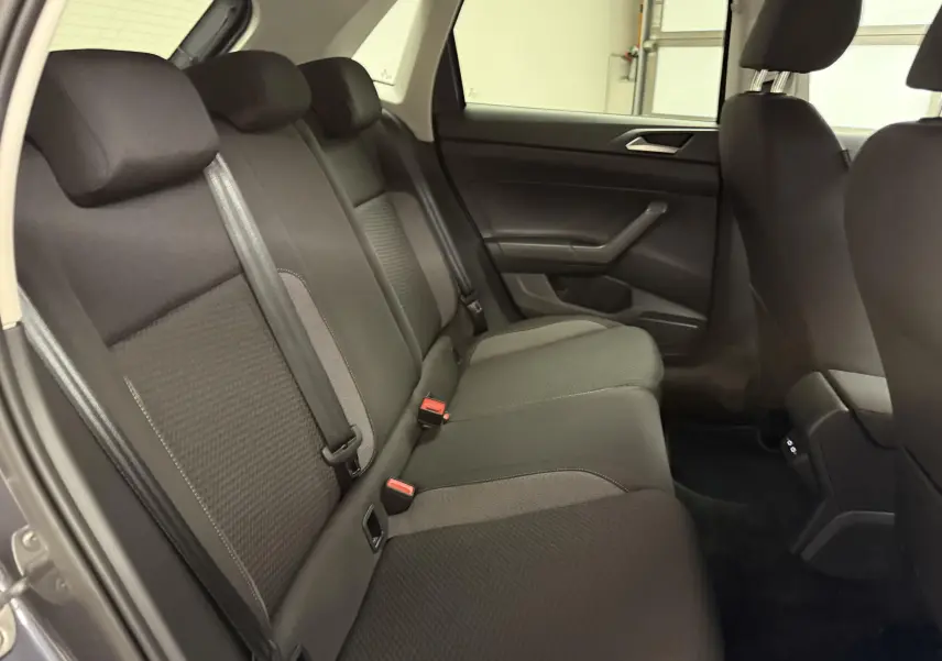 Vue intérieure côté droit de la banquette arrière noire du Volkswagen Polo 2025 gris cendre, avec ceintures de sécurité visibles.