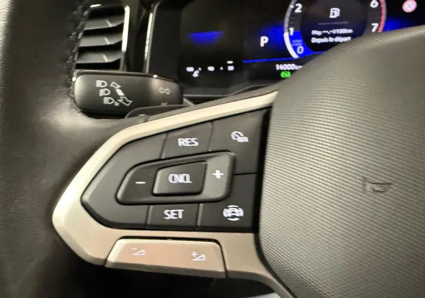 Gros plan sur les commandes de régulateur de vitesse au volant cuir d'une Volkswagen Polo 2025.