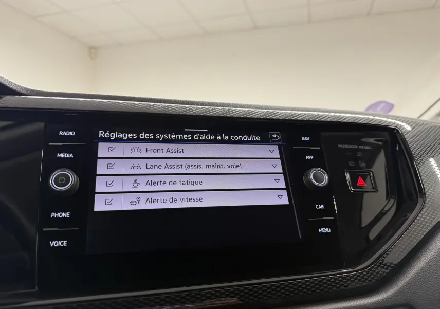 Écran tactile central de la Volkswagen Polo gris cendre affichant les réglages des aides à la conduite.