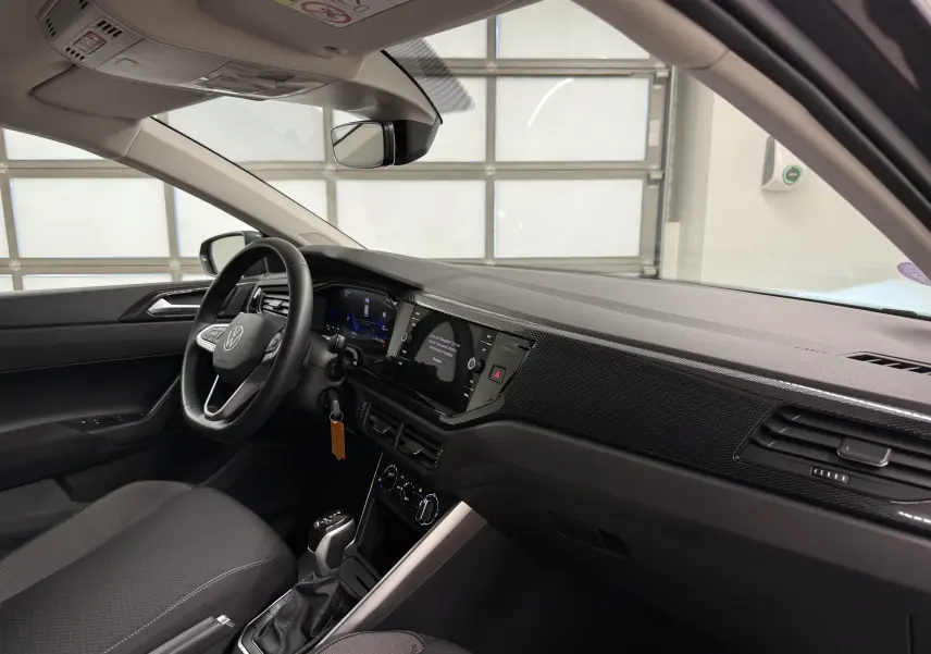 Intérieur avant droit de la Volkswagen Polo gris cendre 2025, tableau de bord moderne avec écran tactile et volant cuir multifonctions.