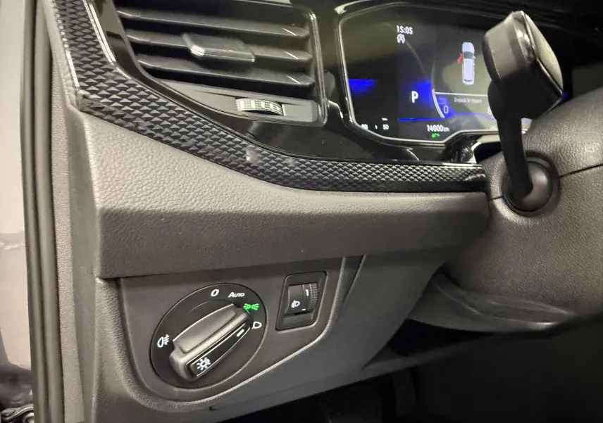 Détail du tableau de bord côté gauche d'une Volkswagen Polo gris cendre, avec commandes d'éclairage et combiné digital.