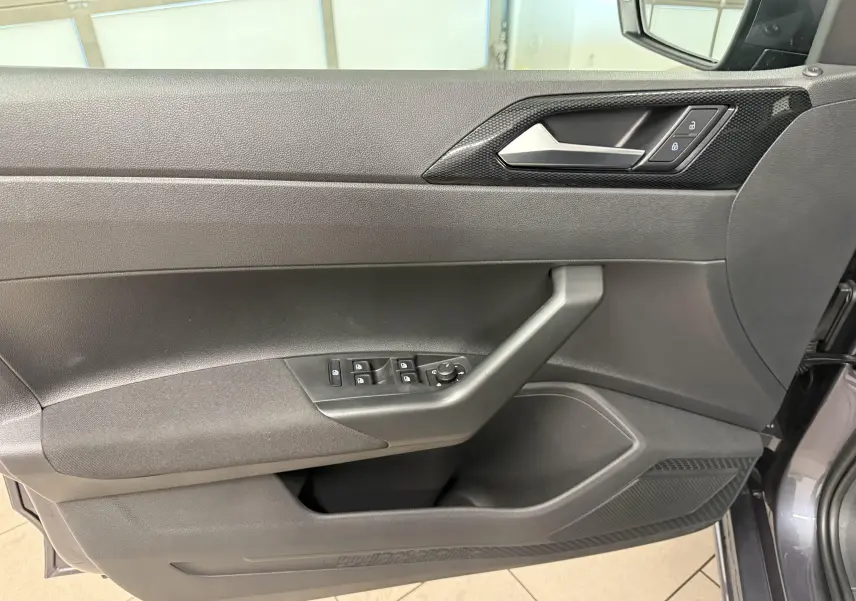 Vue rapprochée de la porte avant gauche de la Volkswagen Polo gris cendre, avec commandes électriques et poignée intégrée.