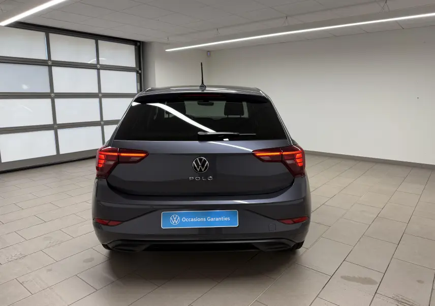 Vue arrière d'une Volkswagen Polo gris cendre 2025 avec feux arrière LED dans un garage lumineux.